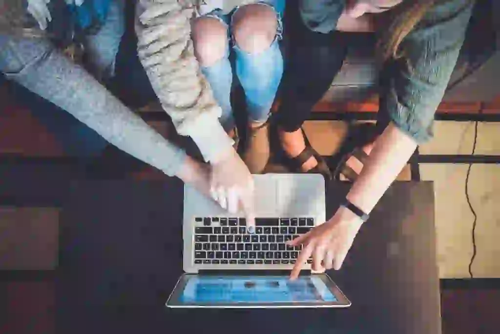 A group of friends gathered around a tablet looking at photos stored on a Synology NAS that is being accessed remotely using QuickConnect