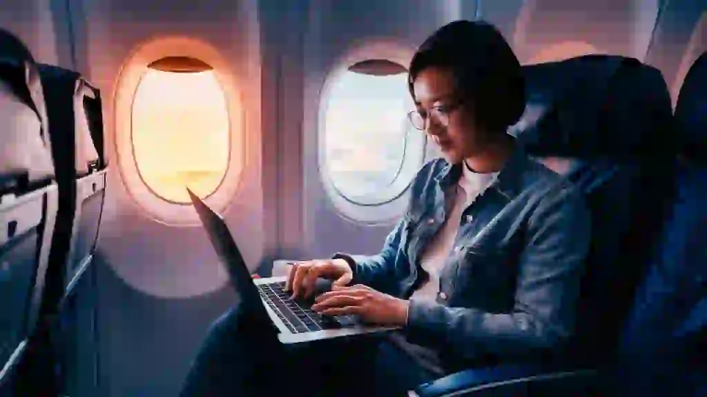 A person working on a laptop on a plane for an extended period with a full battery indicator